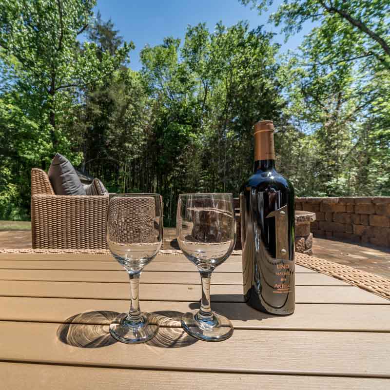 Wine bottle and glasses on outdoor furniture on a patio in Charlotte installed by Benton OUtdoor Living