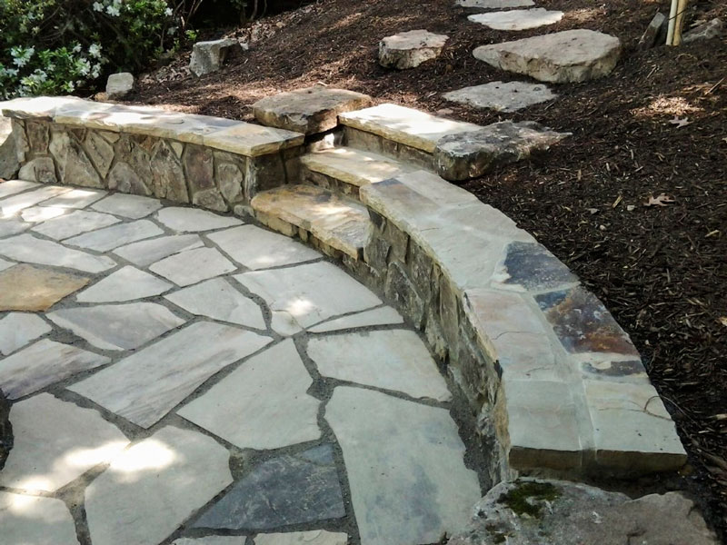 Patio with seat wall and stone steps that was created on a slope using cut and fill
