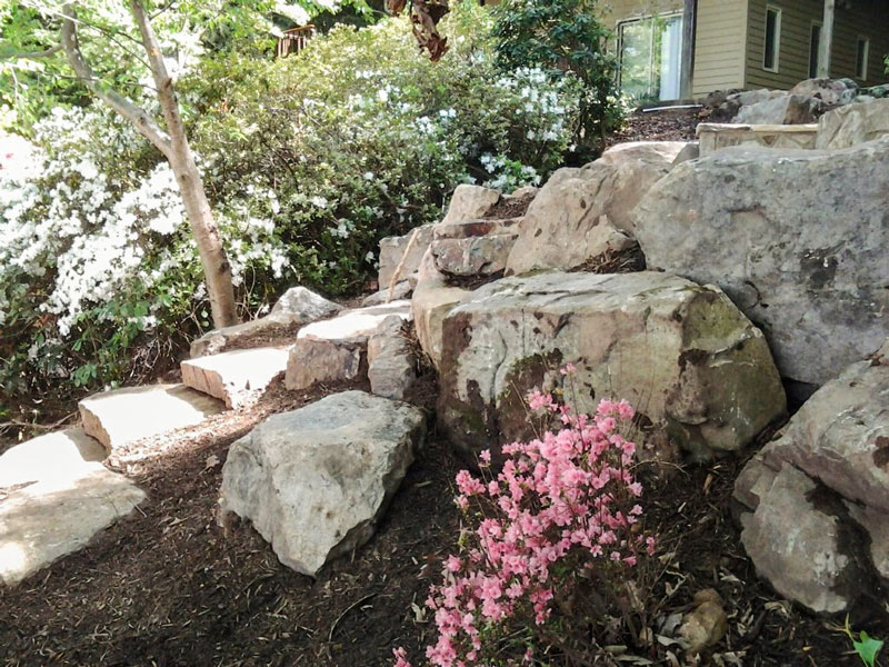 Natural looking rocky outcrop created at base of patio to prevent erosion on a sloped yard