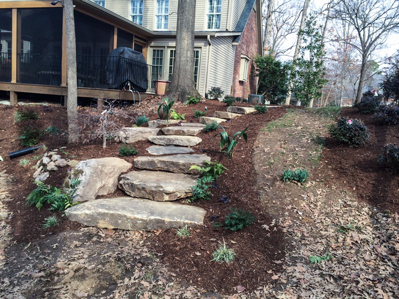 Stone walking steps built into a sloped backyard to provide a walking path down to a flatter area