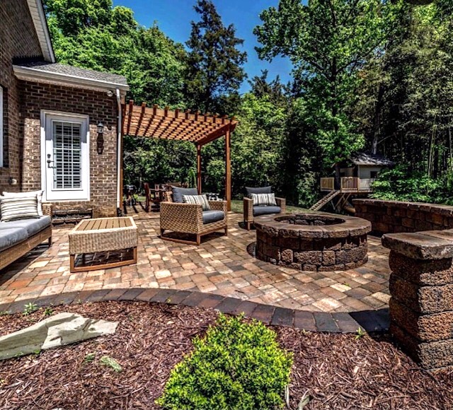 Charlotte backyard after a new paver patio with fire pit and seat wall plus landscaping by Benton Outdoor Living