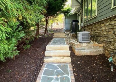 Stone walkway with paver surrounds and stone steps along the side of a house in Charlotte