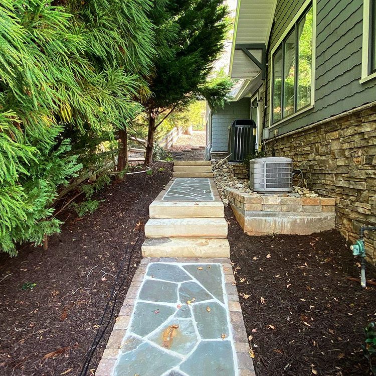 Stone walkway with paver surrounds and stone steps along the side of a house in Charlotte