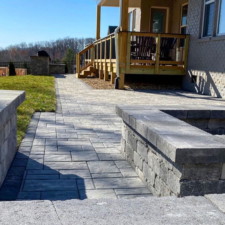 Waxhaw, NC backyard with deck and hardscape consisting of paver walkway, fire pit, grill area and seating walls.