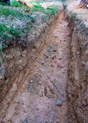 Trench for a french drain that has been dug but the french drain has not yet been installed.