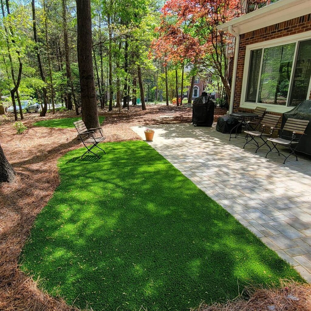 Natural area with a patio and some artificial turf in places it would be hard to mow or hard to grow.