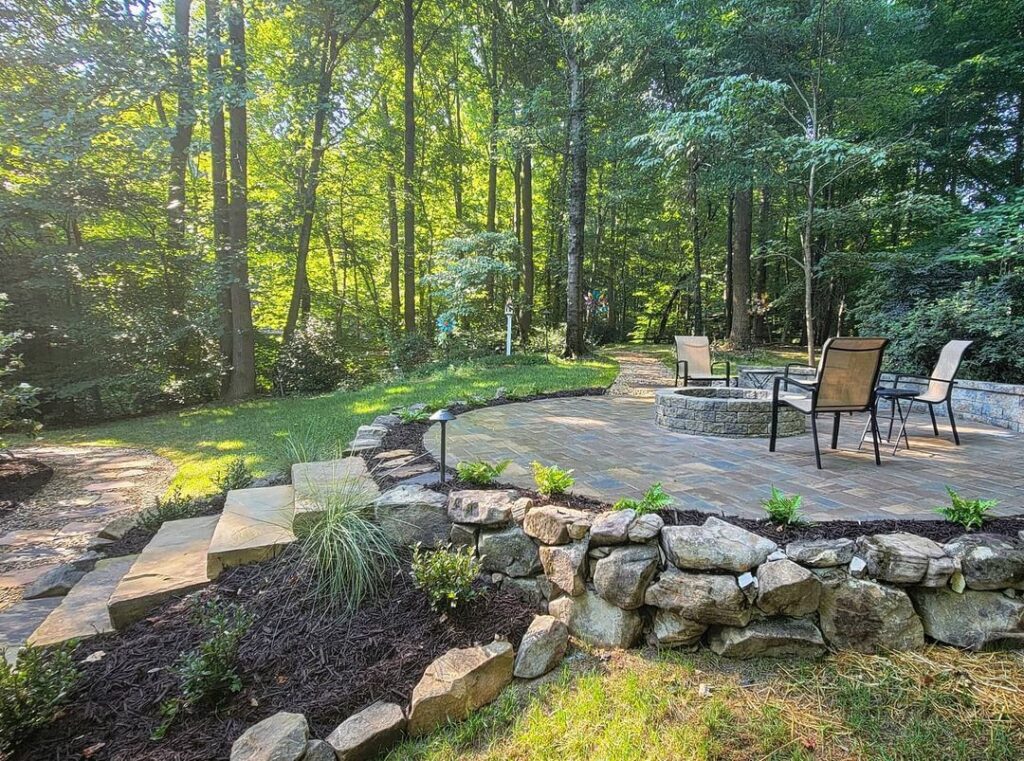 Naturally set patio in a wooded area with landscape lighting placed near stairs for safety.